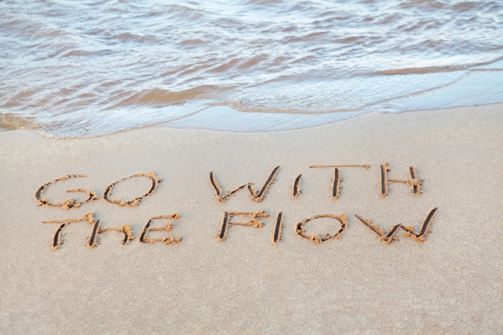 Go with the Flow written in sand